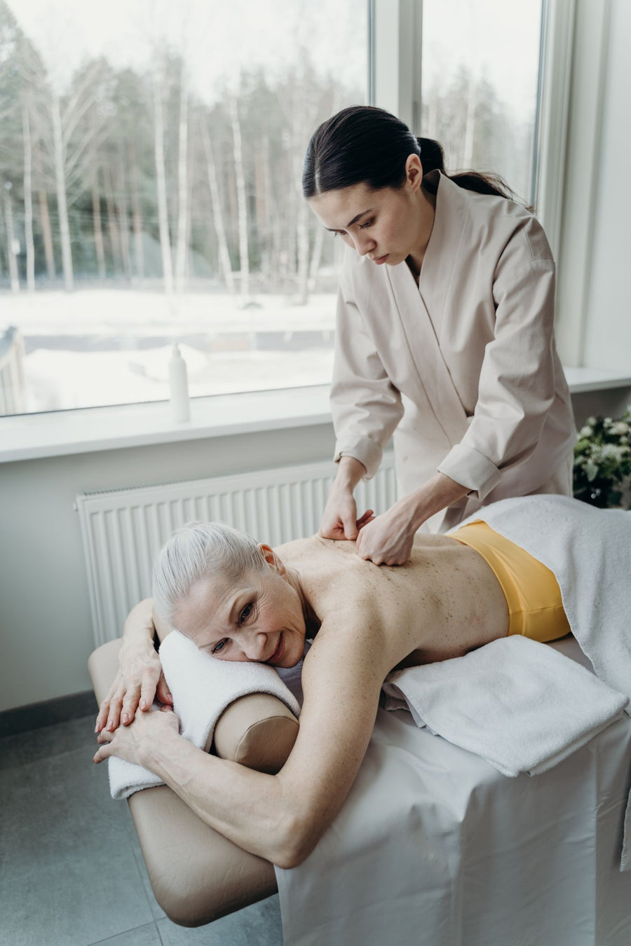 Ältere Frau lächelt bei einer sanften Rückenmassage